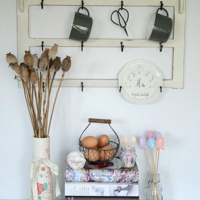 Vignette of kitchen items including cookery books and dried poppy heads in a vase.