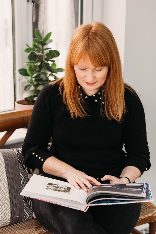 Image of interior designer Claire Parkin sitting on a bench and doing some research by looking in a book.