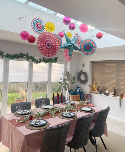 Christmas dining table featuring colourful paper decorations hanging above the table