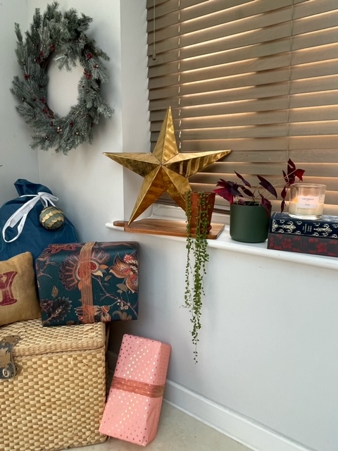 Christmas vignette with wreath, gold star and colourful, wrapped Christmas gifts